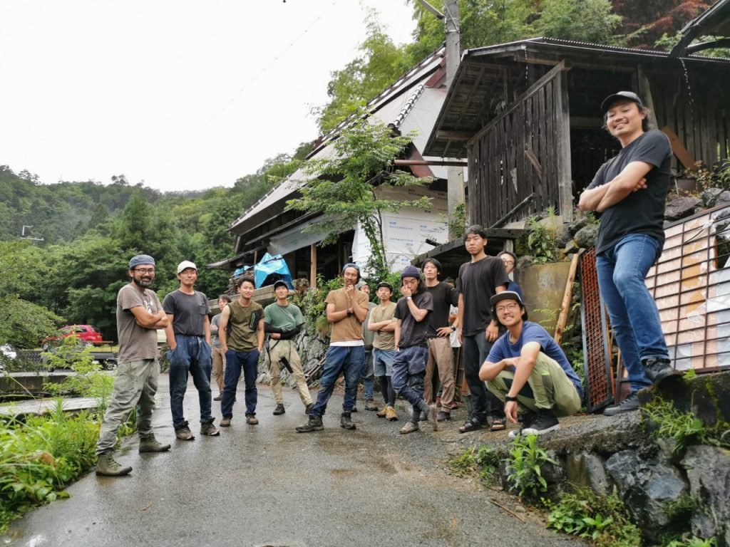 A group of 11 people pose in front of old countryside houses